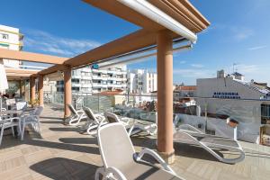 Un balcón con sillas y mesas en un edificio en Apartamentos Guerrero, en Torre del Mar