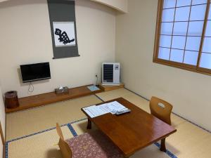 Habitación con mesa, sillas y TV. en Annex Turtle Hotori-An, en Nikko