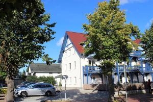 a white house with a car parked in front of it at Ferienwohnung Seeanemone I in Graal-Müritz +1 photo