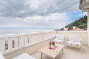 a balcony with two chairs and a table and a view of the ocean at Apartments Kadenca in Omiš