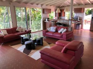 a living room with red couches and a kitchen at Villa Les Trois Moulins in Saint-François