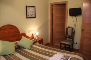 a bedroom with a bed with a clock on the wall at Hostal Maury in El Barraco