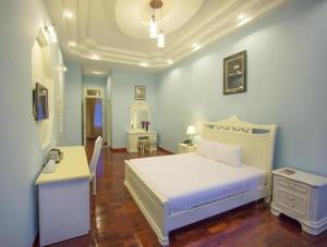a bedroom with a white bed and a desk at Dalat Terrasse Des Roses Villa in Da Lat