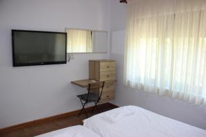 um quarto com uma televisão, uma cama e uma cadeira em Ballo Apartments em Gjirokastër