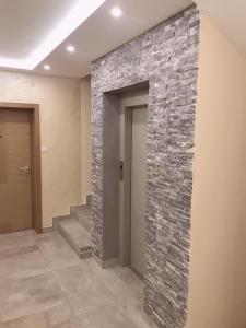 a stone wall in a hallway with a staircase at Apartman Santorini in Novi Sad