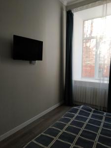 a bedroom with a flat screen tv and a window at Apartmen28juni in Chernivtsi