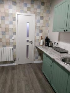 a kitchen with green cabinets and a white door at Apartmen28juni in Chernivtsi