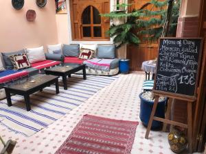 eine Terrasse mit Sofas, Tischen und einer Tafel in der Unterkunft Riad Jenan Adam in Marrakesch