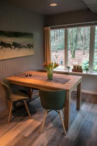een houten tafel in een kamer met stoelen en ramen bij Vakantiehuis 't Musje in Epe