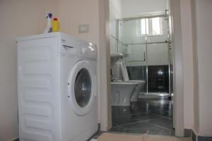 a white washing machine in a bathroom with a shower at Ballo Apartments in Gjirokastër +27 photos