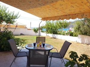 - une table et des chaises sous un parasol sur la terrasse dans l'établissement NAFSIKA Apartments, à Agios Georgios Pagon