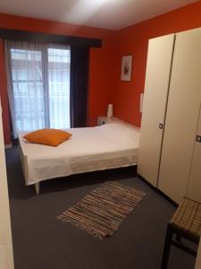 a bedroom with a bed with orange walls and a window at Apartment Havenzicht in Blankenberge