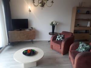 a living room with a tv and two chairs and a table at Apartment Havenzicht in Blankenberge