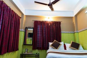 a bedroom with two beds and red curtains at Tirupati Lodge NJP in Siliguri