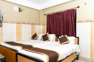 two beds in a room with a red curtain at Tirupati Lodge NJP in Siliguri