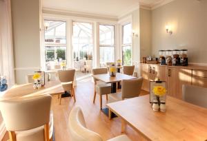 a dining room with tables and chairs and windows at The Castleton in Swanage
