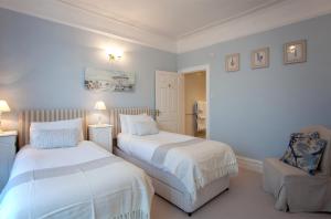 1 dormitorio con 2 camas y 1 silla en The Castleton, en Swanage