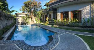 a swimming pool in the yard of a house at Villa Dira Ubud in Ubud