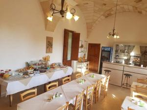 Habitación grande con mesas, sillas y cocina. en Masseria Sucéa, en Martano