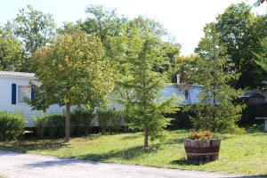 a yard with trees and a white house at Camping du Pontis in Verteillac