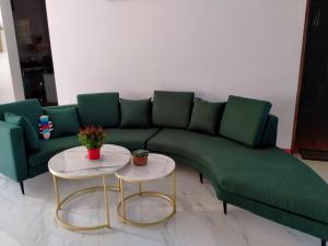 a green couch in a living room with two tables at Kim Lien Phu Quoc Guesthouse in Phú Quốc