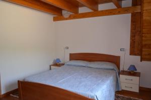 サンタンティーオコにあるCasa Vacanze Cala Saponeのベッドルーム1室(青いシーツと木製の天井が備わるベッド1台付)
