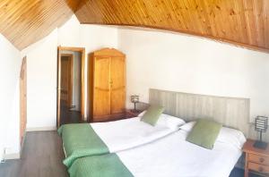 a bedroom with a large bed with white sheets and green pillows at Apartamentos Sabica Nevada Plaza in Sierra Nevada