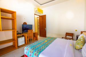 una camera da letto con un letto, una scrivania e una televisione di Gili Sands Hotel & Bar a Gili Trawangan