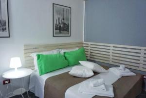 ジャルディーニ・ナクソスにあるyou and meのベッドルーム1室(緑と白の枕が備わるベッド1台付)