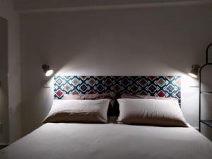 una camera da letto con un grande letto bianco con due cuscini di La Nicuzza-#historicalhouse a Agrigento