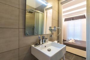 uma casa de banho com um lavatório branco e um espelho. em Venere Bellevue by Babylon Stay em Nápoles