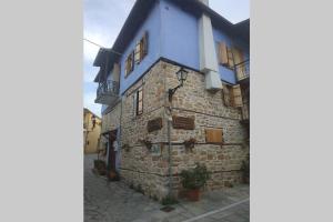 un antiguo edificio de piedra con techo azul y ventanas en ΤΑ ΚΩΝΣΤΑΝΤΑΔΙΚΑ, en Arnaia