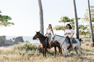 dos mujeres montando caballos en la playa en Star Mountain Jungle Lodge - Mal Pais, Santa Teresa, en Mal País