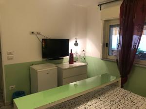 a living room with a television and a green wall at B&B La Terrazza Sul Mare Taormina in Taormina