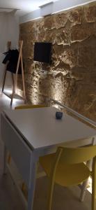 a white table with a chair and a tv on a stone wall at La Nicuzza-#historicalhouse in Agrigento