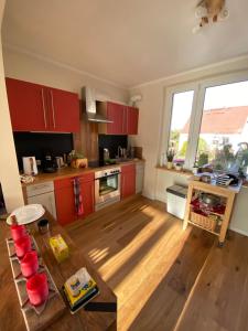 a kitchen with red cabinets and a wooden floor at Ferienhaus "Haus am See" in Prenzlau