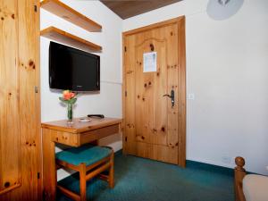 Zimmer mit einem Schreibtisch, einem TV und einer Tür in der Unterkunft Ambiente Guesthouse in Saas-Fee