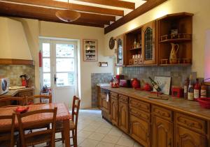 a kitchen with wooden cabinets and a table and a dining room at Gîte rural La Bergerie du Sant in Massaguel