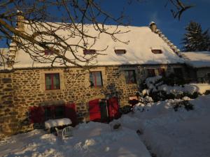 uma casa de pedra com neve no telhado em La Chaumière d'Alambre em Moudeyres