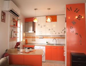 a kitchen with orange cabinets with writing on the wall at CASA KALIMERA in Cuenca