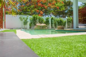 ein Pool in einem Garten mit grünem Gras in der Unterkunft Angel Boutique Hotel in Maputo
