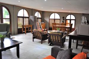 sala de estar con sillas, mesas y ventanas en Flamboyant Guesthouse, en Bela-Bela