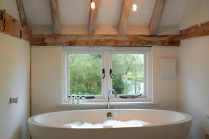 塔登汉姆Tuddenham Mill Luxury Hotel的带窗户的浴室里的浴缸