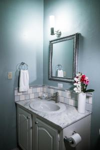 a bathroom with a sink and a mirror and flowers at Connie's Comfort Suites in Saint Johnʼs