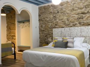 Un dormitorio con una cama grande con una pared de piedra. en LA CASA REBONITA, en Candelario