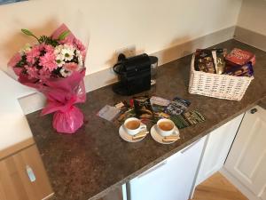 a counter with two cups of coffee and a basket of flowers at Oak Trees Corner stylish , relaxing , getaway in Wicklow