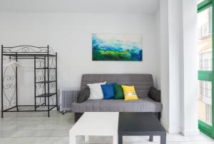 salon z szarą kanapą i kolorowymi poduszkami w obiekcie Livemálaga Panaderos Old Town w Maladze