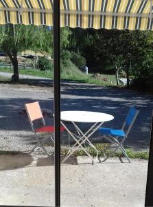 stół i 2 krzesła na zewnątrz okna w obiekcie LES TILLEULS w mieście Riez