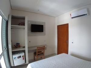Schlafzimmer mit einem Bett, einem TV und einem Stuhl in der Unterkunft Casablanca Palace Hotel in Frutal