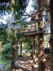 a woman sitting on a tree house in a forest at Willa Brzozówka in Milówka